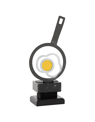 Trofeo de cocina de metal cortado con láser y con forma de una paella haciendo un huevo frito, con la base oscura.